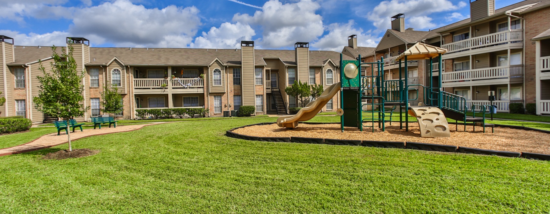 Outdoor green space and playground area at Oaks at Greenview apartments in Houston, Texas
